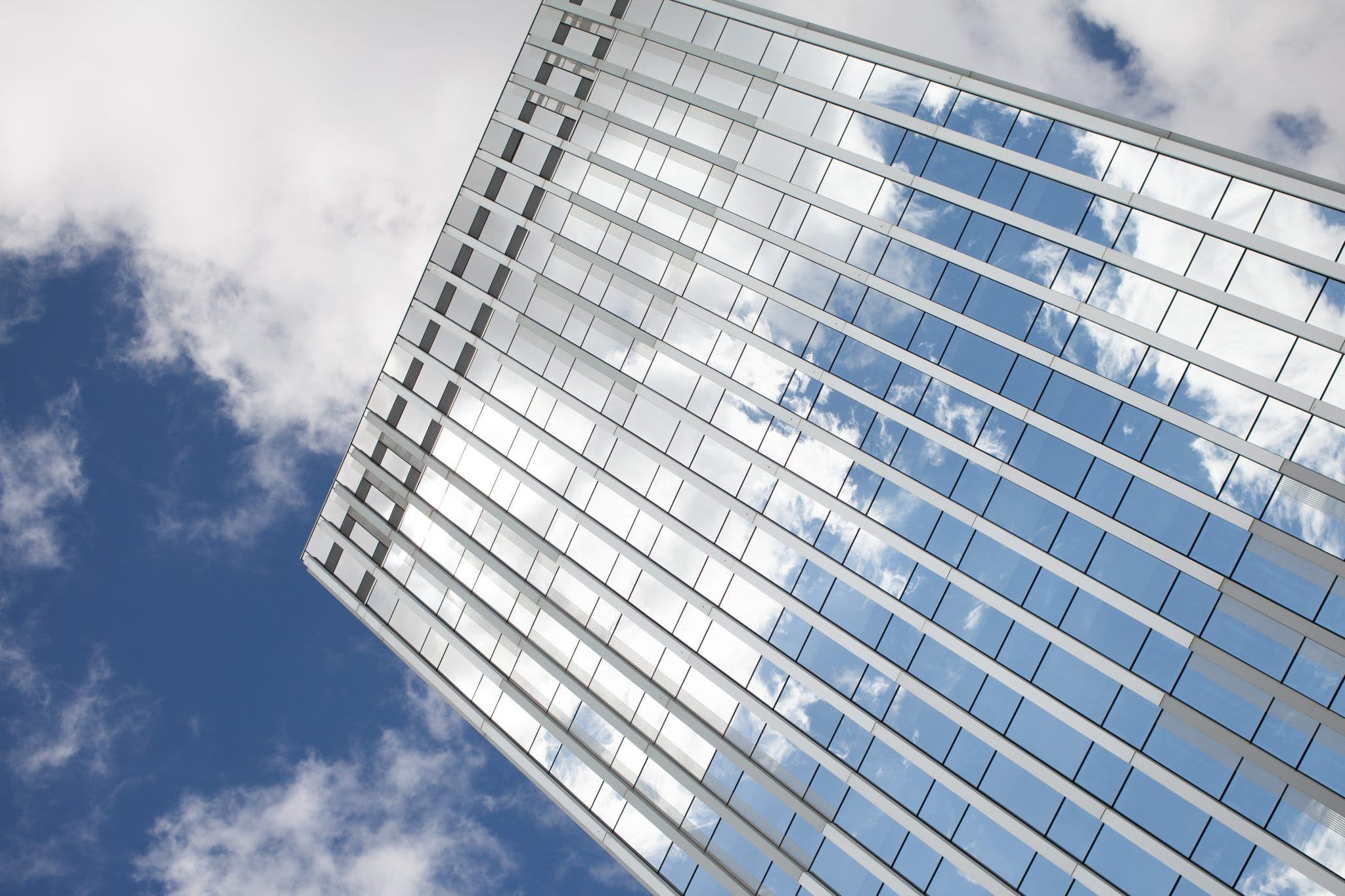 Immeuble de bureaux vitré reflétant un ciel bleu